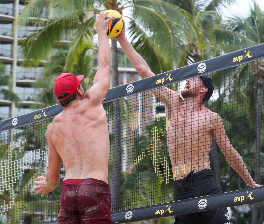 Two beach volleyball athletes compete for a joust